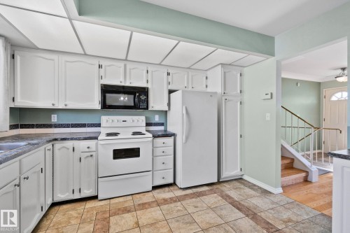 The kitchen features white cabinetry, a white electric range, and a white refrigerator - 2016 138 Avenue, Edmonton, AB - Indoor Photo Showing Kitchen
