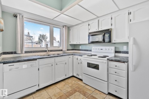 Kitchen featuring white cabinetry, a double basin sink, and a window providing natural light - 2016 138 Avenue, Edmonton, AB - Indoor Photo Showing Kitchen With Double Sink