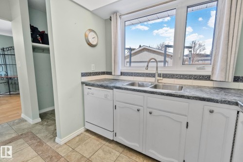 The kitchen features a double stainless steel sink with a modern faucet, white cabinetry, and a dishwasher - 2016 138 Avenue, Edmonton, AB - Indoor Photo Showing Kitchen With Double Sink