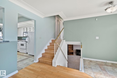 The property features hardwood floors, a staircase with a white railing and brass handrail, and light blue painted walls - 2016 138 Avenue, Edmonton, AB - Indoor Photo Showing Other Room