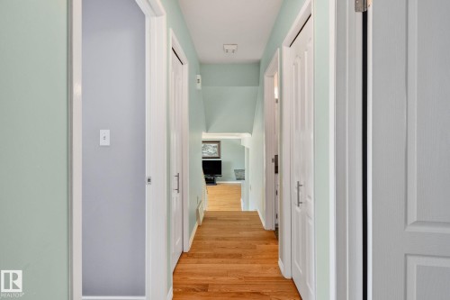 Hallway featuring hardwood floors, light blue walls, and white paneled doors with silver handles - 2016 138 Avenue, Edmonton, AB - Indoor Photo Showing Other Room
