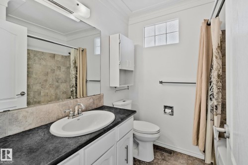 Bathroom featuring a vanity with a dark countertop and white sink, a mirror, and a shower with tile surround - 2016 138 Avenue, Edmonton, AB - Indoor Photo Showing Bathroom