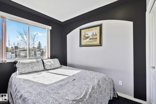 Bedroom featuring a window providing natural light, a white door, and a decorative wall niche - 2016 138 Avenue, Edmonton, AB - Indoor Photo Showing Bedroom