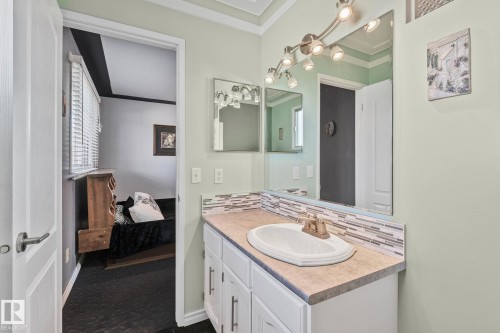 Ensuite bathroom vanity with a single sink, an integrated backsplash, and a large mirror with track lighting - 2016 138 Avenue, Edmonton, AB - Indoor Photo Showing Bathroom