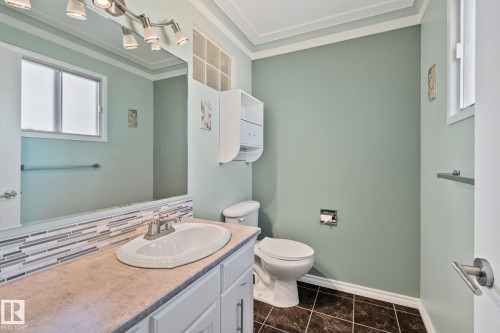 Ensuite Bathroom featuring a vanity with a countertop and sink, a mirror with overhead lighting, a window, and a toilet - 2016 138 Avenue, Edmonton, AB - Indoor Photo Showing Bathroom