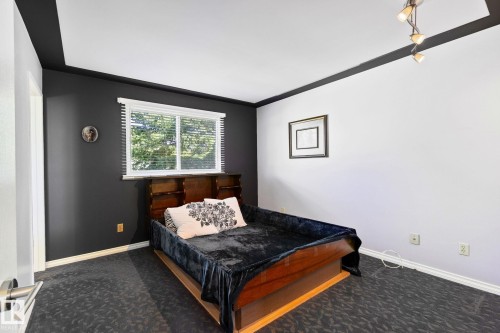 The room features a window with blinds, dark accent walls, and a patterned carpet - 2016 138 Avenue, Edmonton, AB - Indoor Photo Showing Bedroom