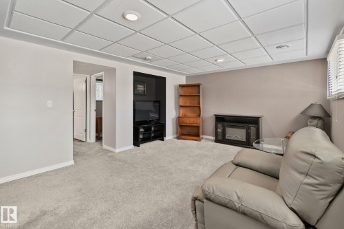 This spacious room features light grey carpeting, recessed lighting, and a window with blinds - 2016 138 Avenue, Edmonton, AB - Indoor With Fireplace