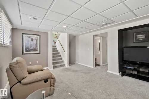 This area features light-colored carpeting, a drop ceiling with recessed lighting, and a window with blinds - 2016 138 Avenue, Edmonton, AB - Indoor Photo Showing Other Room