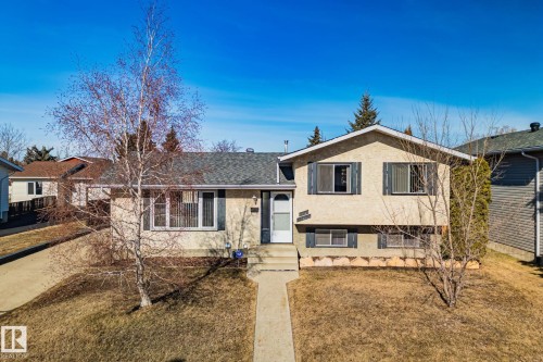 The property features a stucco exterior, a concrete walkway leading to the front entrance, and a driveway - 2016 138 Avenue, Edmonton, AB - Outdoor