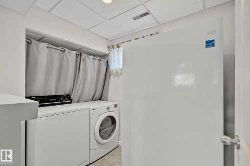 Dedicated laundry area featuring a washer and dryer, with overhead storage concealed by curtains - 2016 138 Avenue, Edmonton, AB - Indoor Photo Showing Laundry Room