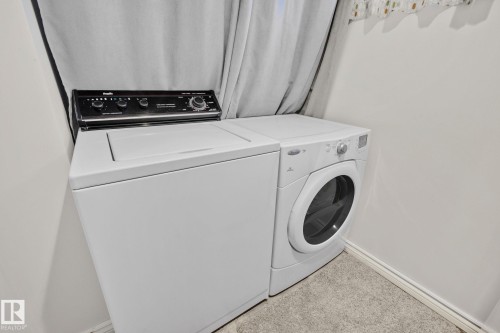 Dedicated laundry area with a top-loading washing machine and a front-loading dryer, set on a carpeted floor - 2016 138 Avenue, Edmonton, AB - Indoor Photo Showing Laundry Room