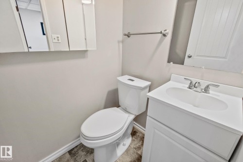 Bathroom featuring a white vanity with an integrated sink, a matching white toilet, and a medicine cabinet with an integrated light fixture - 2016 138 Avenue, Edmonton, AB - Indoor Photo Showing Bathroom