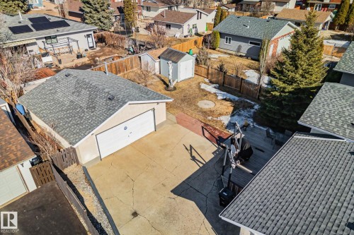 Detached garage with a driveway, featuring a fenced yard with a shed and mature trees - 2016 138 Avenue, Edmonton, AB - Outdoor