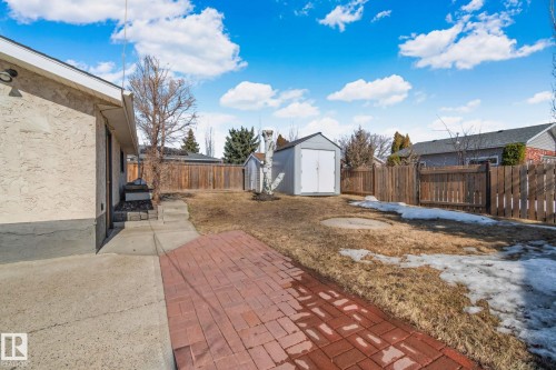 The property features a spacious yard with a wooden privacy fence, a storage shed, and a red brick patio area - 2016 138 Avenue, Edmonton, AB - Outdoor