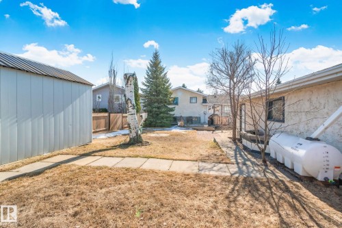 The property features a spacious yard with a storage shed, established trees, and a paved pathway - 2016 138 Avenue, Edmonton, AB - Outdoor