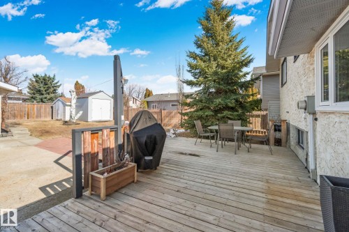 The property features a spacious wooden deck, perfect for outdoor enjoyment, and a substantial yard area with a mature evergreen tree - 2016 138 Avenue, Edmonton, AB - Outdoor With Deck Patio Veranda With Exterior