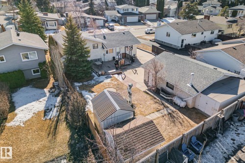 The property features an extensive yard with a lawn, mature evergreen trees, and a wooden fence - 2016 138 Avenue, Edmonton, AB - Outdoor