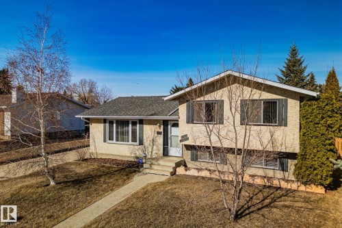 The property features a stucco exterior, a grey shingled roof, and a paved walkway leading to the front entrance - 2016 138 Avenue, Edmonton, AB - Outdoor
