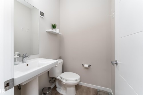 This powder room features a white pedestal sink with a chrome faucet, a toilet, and light-toned flooring - 22742 95A Ave, Edmonton, AB - Indoor Photo Showing Bathroom
