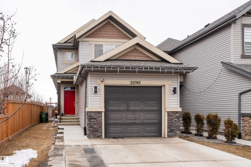 This property features a two-story exterior with light-colored siding and stone accents - 22742 95A Ave, Edmonton, AB - Outdoor