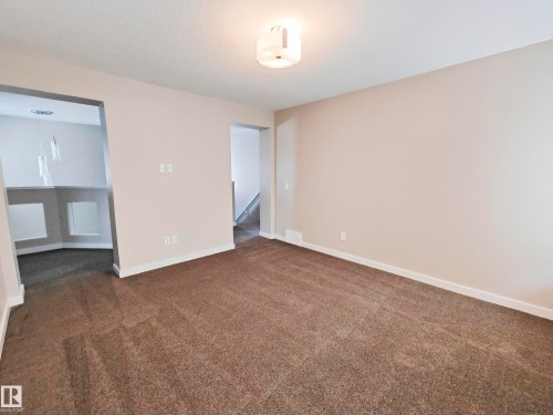 This room features neutral-toned carpet and walls, along with white baseboards and trim - 8008 18 Avenue Sw, Edmonton, AB - Indoor Photo Showing Other Room