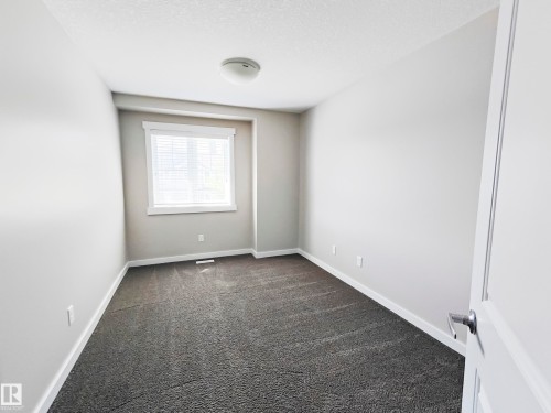 The property features a room with gray carpet, a window with white blinds, and light-colored walls - 8008 18 Avenue Sw, Edmonton, AB - Indoor Photo Showing Other Room