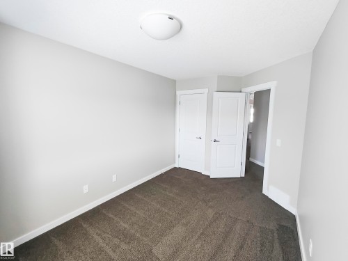 The room features neutral-toned walls, dark patterned carpeting, and white trim - 8008 18 Avenue Sw, Edmonton, AB - Indoor Photo Showing Other Room