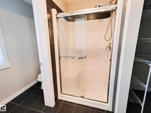 Bathroom featuring a stand-up shower with a clear glass enclosure, brushed nickel fixtures, and a built-in seat - 8008 18 Avenue Sw, Edmonton, AB - Indoor Photo Showing Bathroom