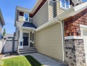The property features a dark-colored front door, a covered porch with a white column, and a light green siding exterior - 8008 18 Avenue Sw, Edmonton, AB  - Outdoor 