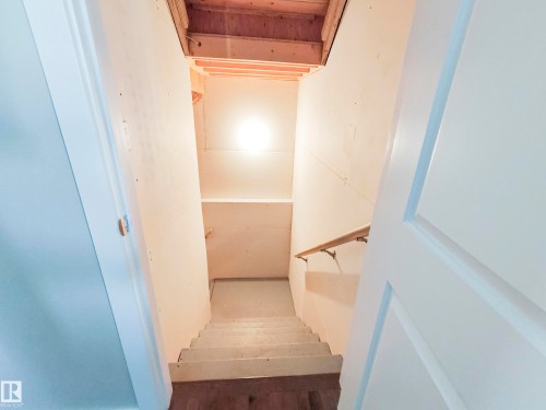 Stairway featuring white walls, a wooden handrail, and exposed ceiling joists - 8008 18 Avenue Sw, Edmonton, AB - Indoor Photo Showing Other Room