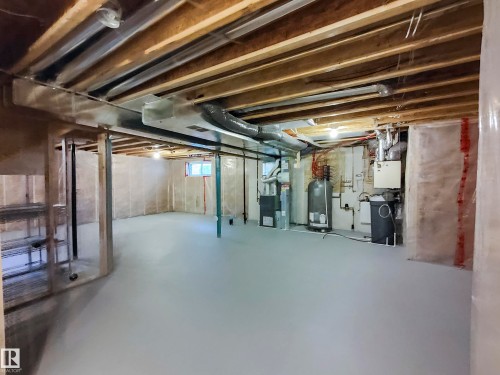 Expansive unfinished basement featuring a light gray painted concrete floor, exposed ceiling joists, and a window providing natural light - 8008 18 Avenue Sw, Edmonton, AB - Indoor Photo Showing Basement