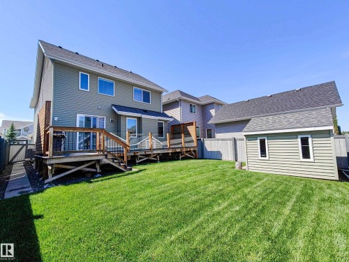 The property features a spacious backyard with a well-maintained lawn, a wooden deck with glass railings, and a storage shed - 8008 18 Avenue Sw, Edmonton, AB - Outdoor With Deck Patio Veranda With Exterior
