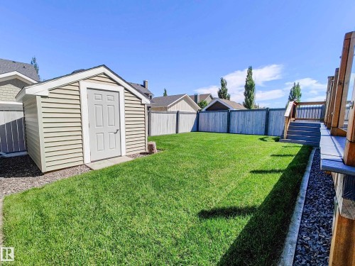The property includes a spacious, well-maintained lawn, a storage shed with siding, and a wooden fence along the perimeter - 8008 18 Avenue Sw, Edmonton, AB - Outdoor