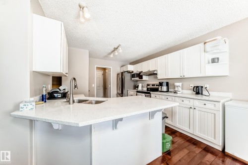 Kitchen featuring white cabinetry, light-colored countertops, and hardwood flooring - 19024 50 Avenue, Edmonton, AB - Indoor Photo Showing Kitchen With Double Sink
