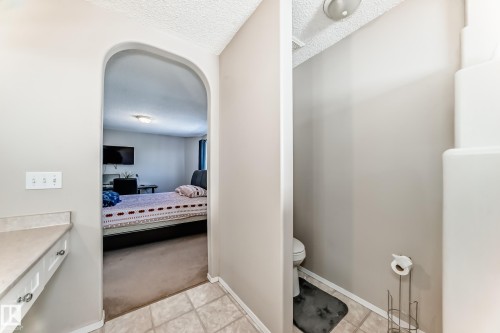 Archway leading to a carpeted room with a bed and a wall-mounted television - 19024 50 Avenue, Edmonton, AB - Indoor