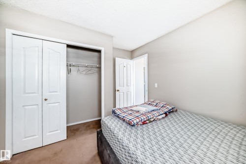 This room features a closet with bi-fold doors, wall-to-wall carpeting, and light-colored walls - 19024 50 Avenue, Edmonton, AB - Indoor Photo Showing Bedroom