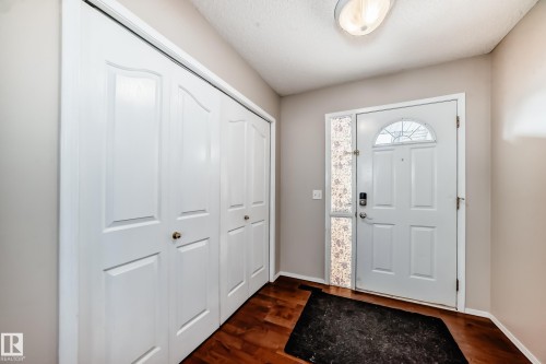 The entryway features a white front door with an arched window, a white interior door, and dark wood flooring - 19024 50 Avenue, Edmonton, AB - Indoor Photo Showing Other Room