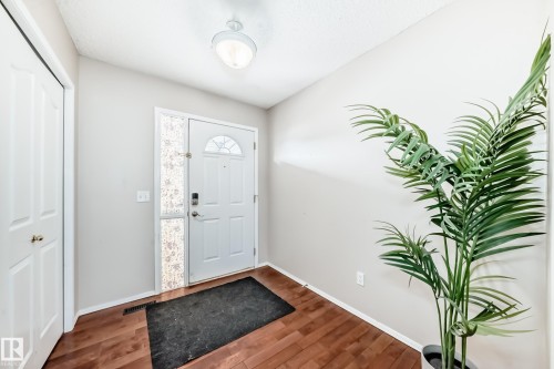 Inviting entryway featuring warm-toned wood flooring, a white paneled door with decorative glass, and a functional closet - 19024 50 Avenue, Edmonton, AB - Indoor Photo Showing Other Room