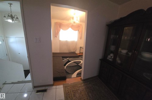 This interior view showcases various flooring types including white tiled flooring, a patterned area rug, and hardwood flooring - 16912 110 Street, Edmonton, AB - Indoor Photo Showing Other Room
