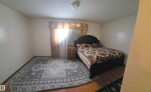 This room features hardwood flooring, a window with drapery, and a ceiling light fixture - 16912 110 Street, Edmonton, AB - Indoor Photo Showing Bedroom