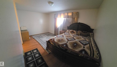 This room features light-colored walls and hardwood flooring, complemented by a decorative area rug - 16912 110 Street, Edmonton, AB - Indoor Photo Showing Bedroom