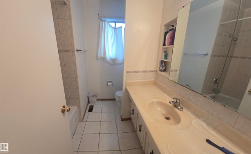 Bathroom featuring a window, tile flooring, a vanity with an integrated sink, and a mirrored medicine cabinet - 16912 110 Street, Edmonton, AB - Indoor Photo Showing Bathroom