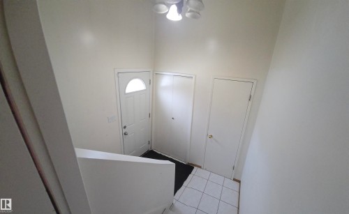 The property features a front door with an arched window, white walls, and a white tiled floor in the entryway - 16912 110 Street, Edmonton, AB - Indoor Photo Showing Other Room