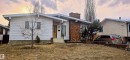 The property features a white exterior, a brick chimney, and a wooden front door - 16912 110 Street, Edmonton, AB  - Outdoor 