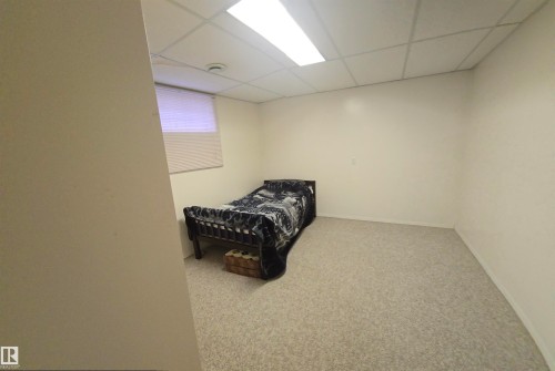 This room features light-colored carpet, white walls, and a drop ceiling with integrated lighting - 16912 110 Street, Edmonton, AB - Indoor