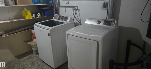 Laundry area featuring a white washing machine and dryer, with shelving for storage - 16912 110 Street, Edmonton, AB - Indoor Photo Showing Laundry Room