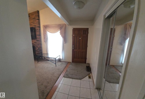 The entryway features tile flooring, a paneled front door, and a mirrored closet - 16912 110 Street, Edmonton, AB - Indoor Photo Showing Other Room