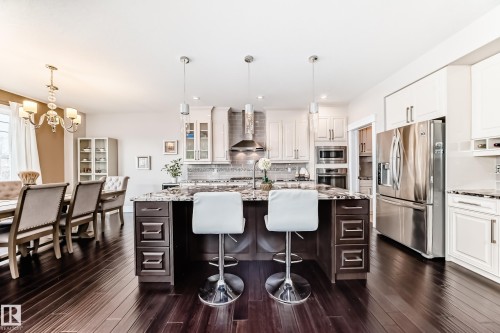 This kitchen features extensive dark hardwood flooring, a large island with a granite countertop, and stainless steel appliances - 4134 Charles Link, Edmonton, AB - Indoor