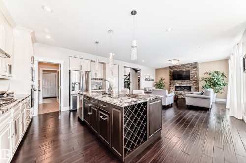 Open concept living area featuring dark hardwood floors, a kitchen island with a granite countertop, and stainless steel appliances - 4134 Charles Link, Edmonton, AB - Indoor Photo Showing Kitchen With Upgraded Kitchen