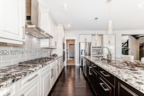 The kitchen features a gas cooktop with a stainless steel range hood, white cabinetry, and granite countertops - 4134 Charles Link, Edmonton, AB - Indoor Photo Showing Kitchen With Upgraded Kitchen